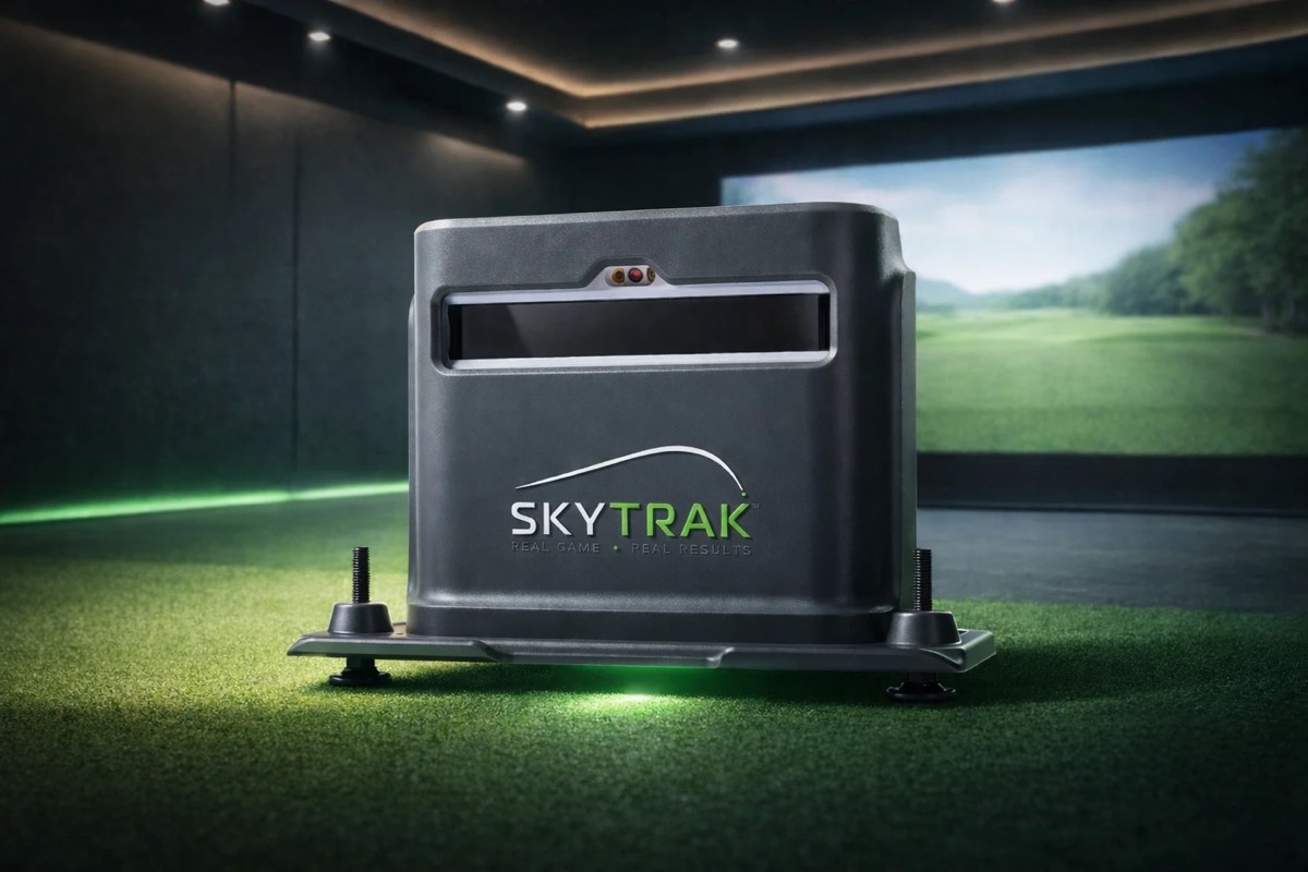 SkyTrak launch monitor sitting on a hitting mat in front of a simulator screen